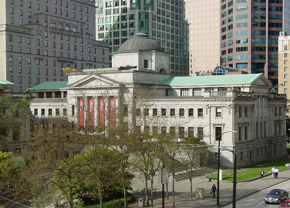 Historic public library in downtown cityscape Historic public library building with classical architecture and green roof in urban downtown area with skyscrapers