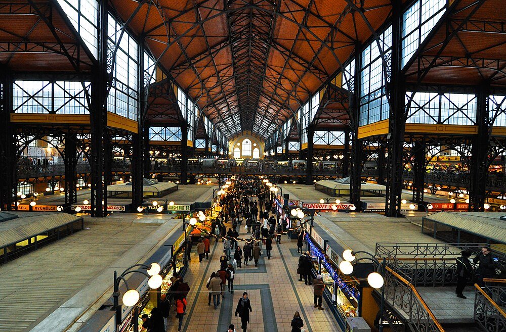 Historic Market Hall Interior with Shoppers Interior view of a large historic market hall with high ceilings, iron beams, and numerous shoppers walking through stalls