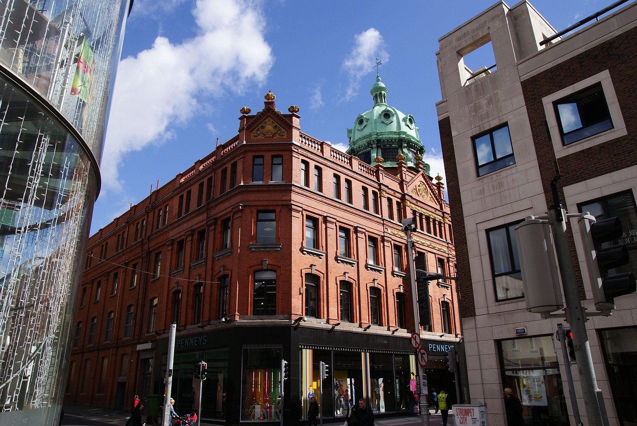 Historic red brick building with green dome and Penneys store on a sunny day in a busy city street