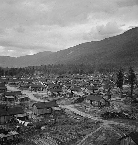 Historic rural village with wooden houses and mountains Historic black and white photo of a small rural village with wooden houses and mountainous landscape in the background