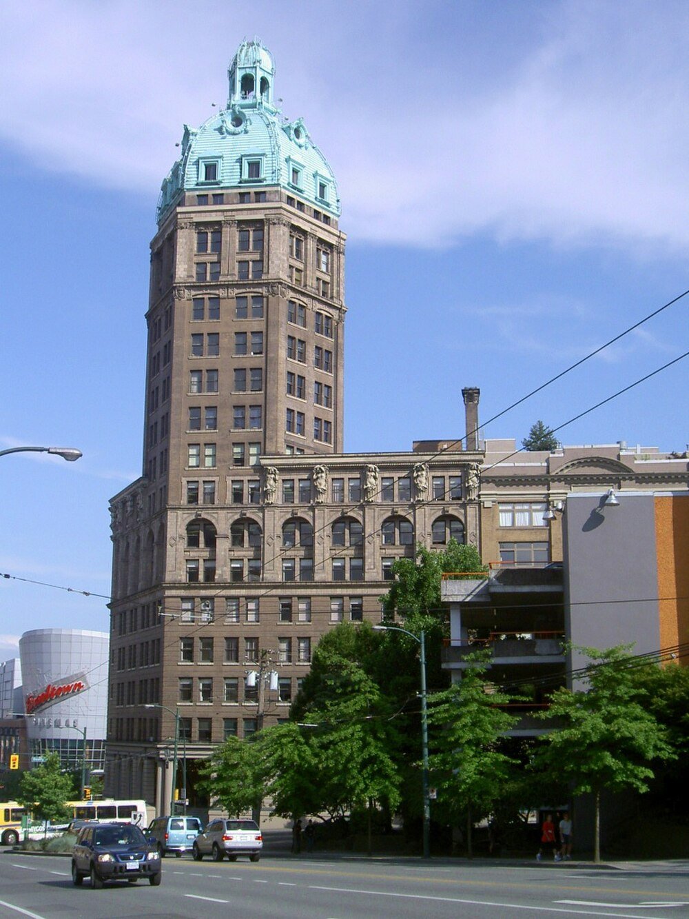 Historic tower with green dome in city Historic tower building with green dome roof in urban cityscape with cars and trees on a sunny day