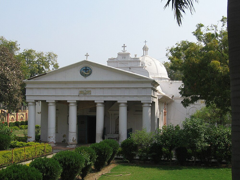 Historic White Church with Columns and Crosses Historic white church building with columns and crosses surrounded by green trees and lawn under clear sky