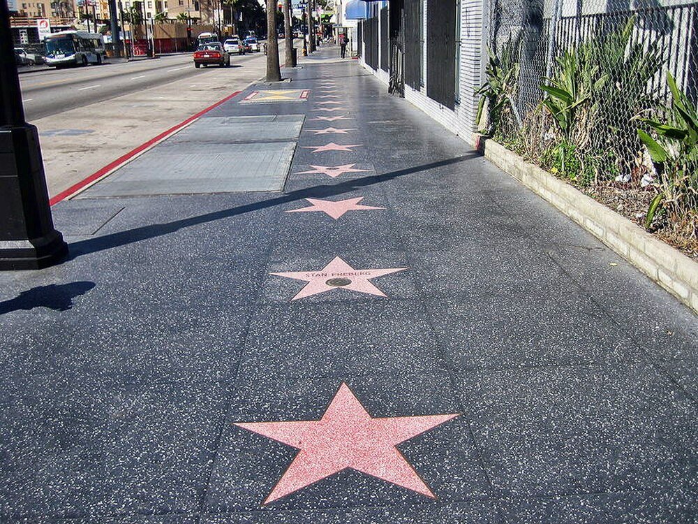 Hollywood Walk of Fame stars on sidewalk Hollywood Walk of Fame stars embedded in sidewalk along a busy street with cars and buildings in the background