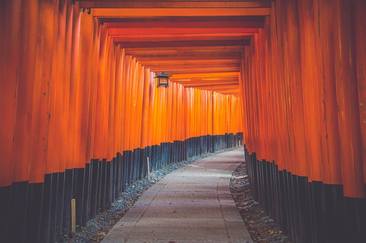 Pathway through traditional Japanese torii gates painted orange and black at Fushimi Inari Shrine in Kyoto