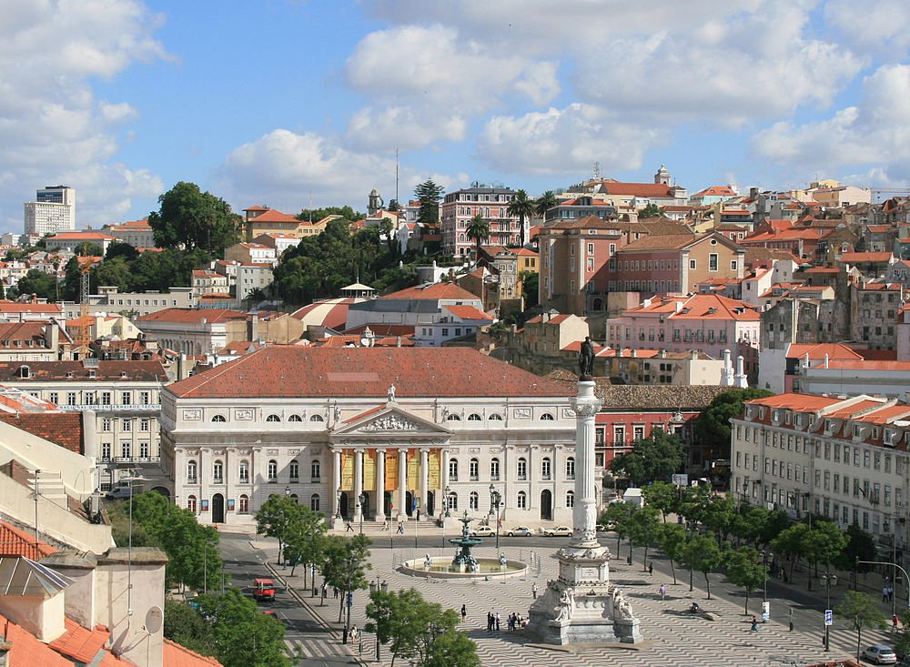 Lisbon city center with monument and historic buildings Scenic view of Lisbon city center with historic buildings, a monument, and a patterned plaza under a blue sky