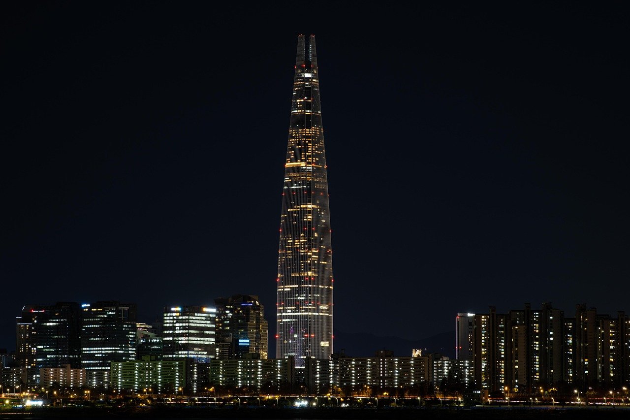 Night view of Lotte World Tower illuminated with city buildings in Seoul, South Korea, showcasing modern skyscrapers and urban skyline.