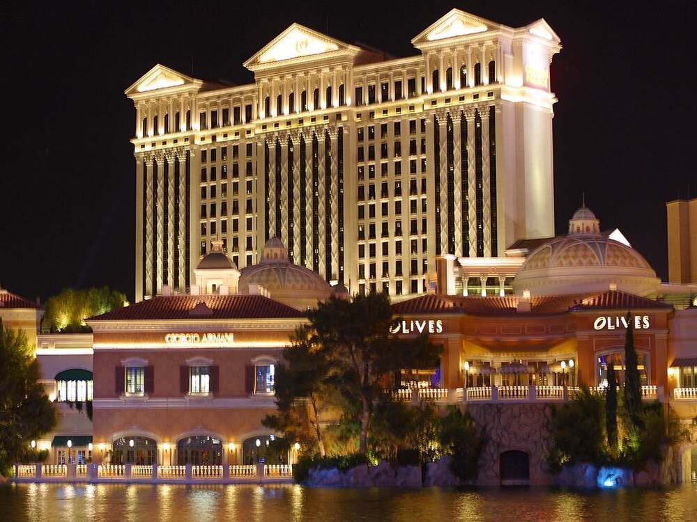 Night view of a luxury hotel and casino with illuminated classical architecture and waterfront reflection