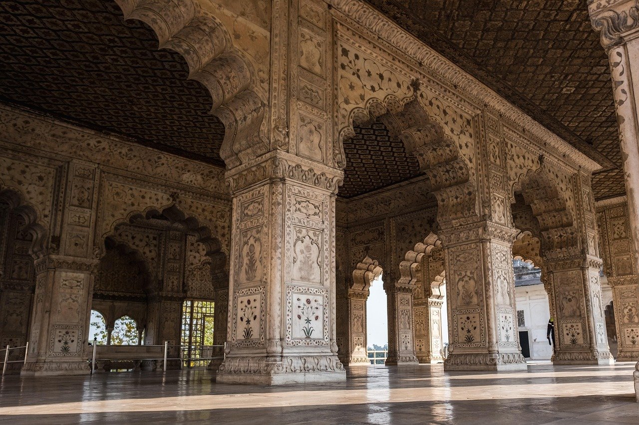 Intricately carved marble arches and pillars with floral designs in a historic Indian palace interior