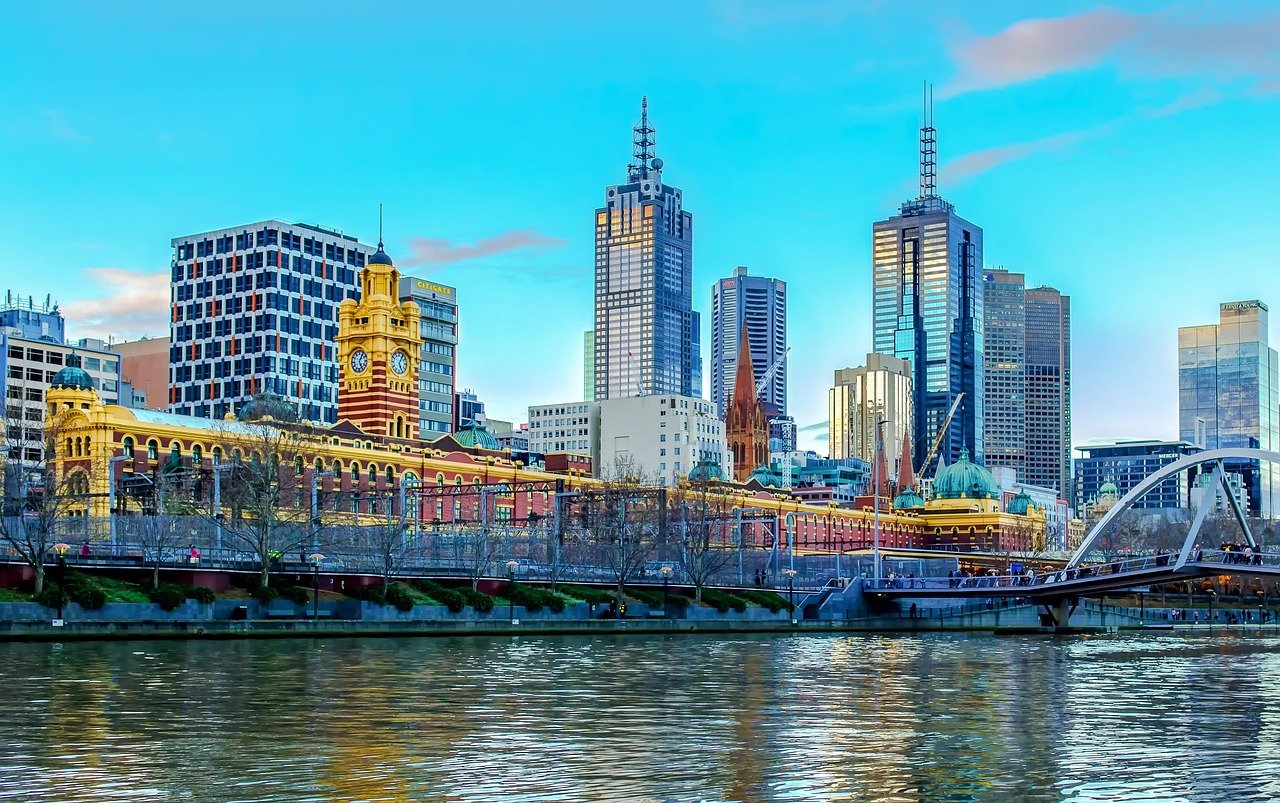 Melbourne city skyline with Yarra River, Flinders Street Station, and modern skyscrapers under a clear blue sky
