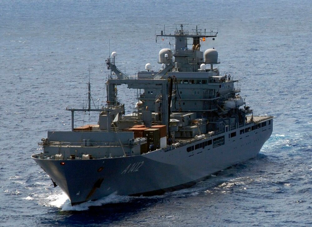Military supply ship A142 at sea Large gray military supply ship A142 sailing on calm blue ocean water with containers on deck