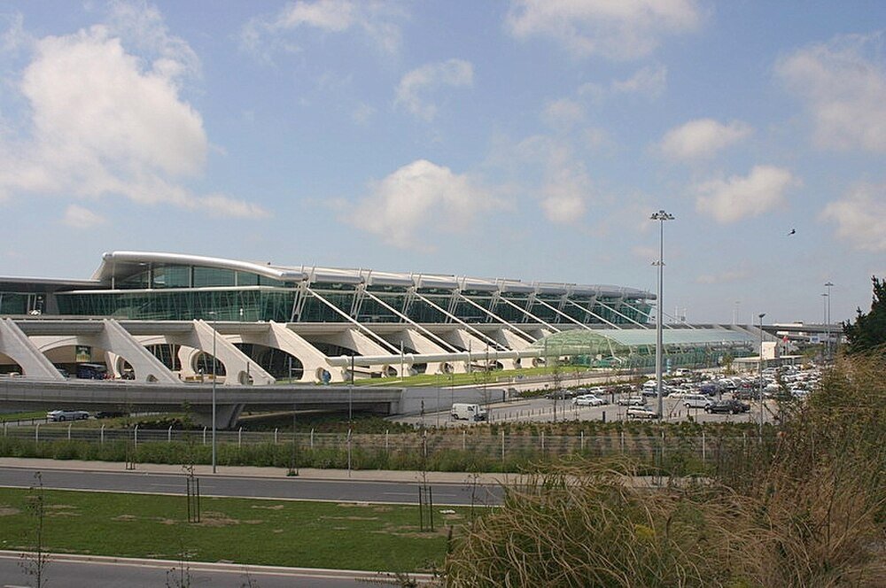 Modern airport terminal with parking lot Modern airport terminal building with glass facade, parking lot, and clear blue sky on a sunny day
