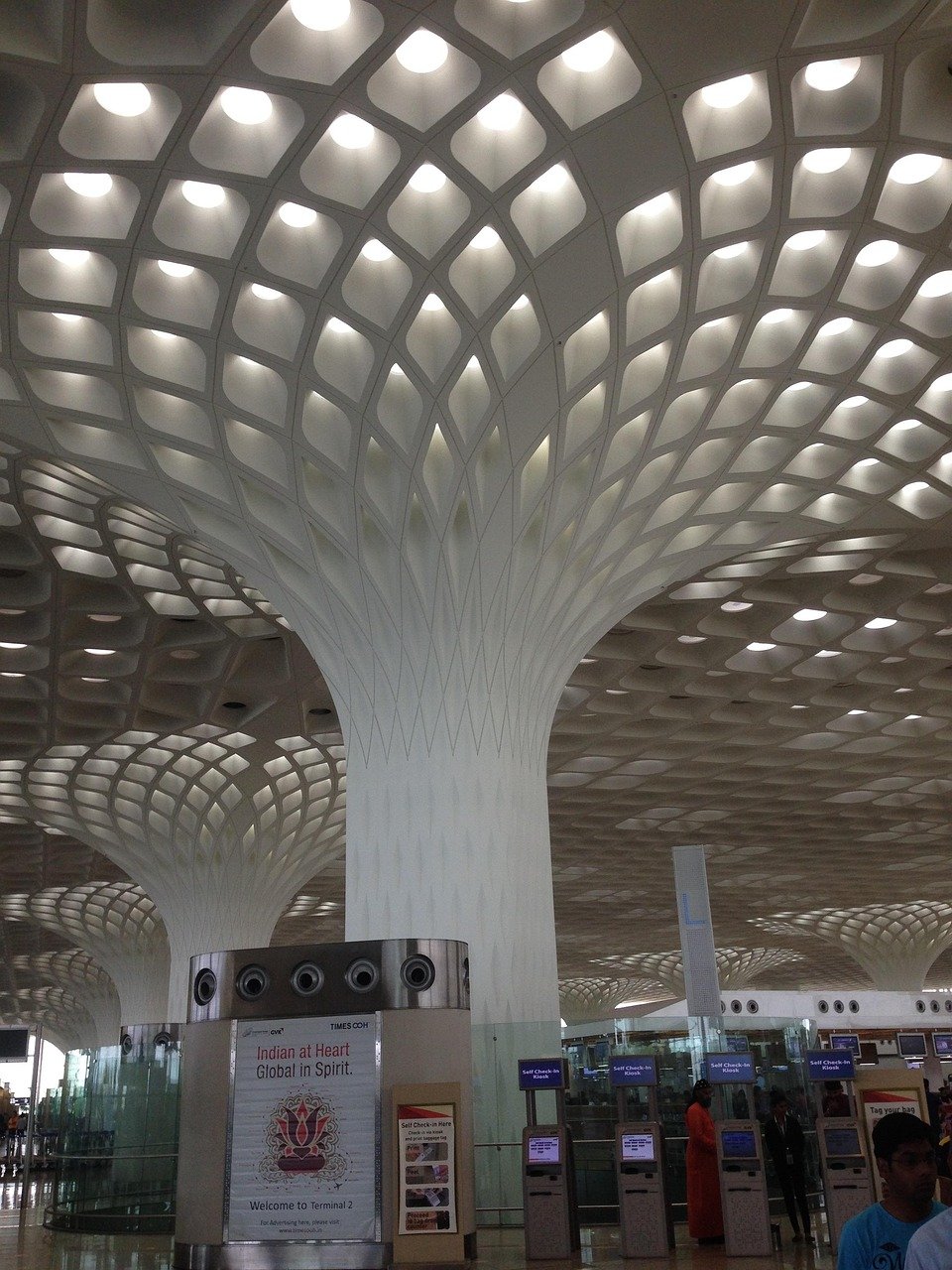 Modern airport terminal interior with unique honeycomb ceiling design and self check-in kiosks in Terminal 2