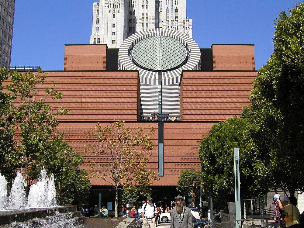 Modern art museum with circular window and brick facade Modern art museum with distinctive circular window and brick facade, surrounded by trees and people in an urban park setting