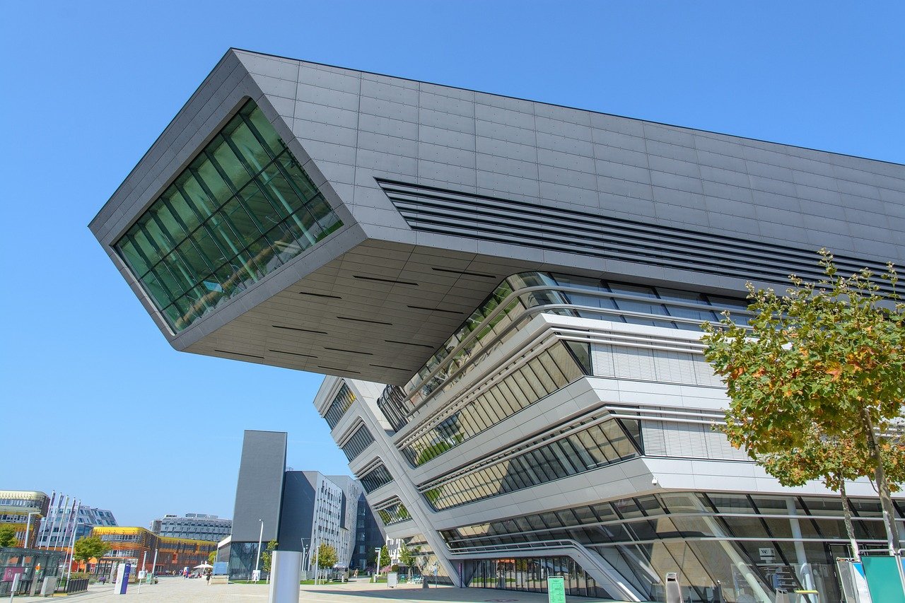 Modern futuristic university building with angular design and large glass windows under clear blue sky
