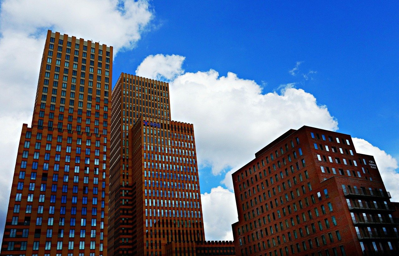 Modern high-rise office buildings under a bright blue sky with white clouds in an urban cityscape