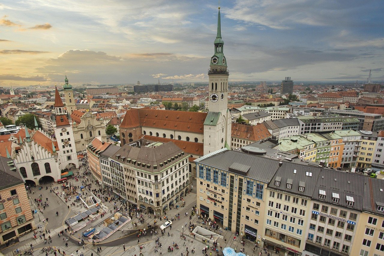 Aerial view of Munich city center with historic buildings, clock tower, and bustling pedestrian streets at sunset