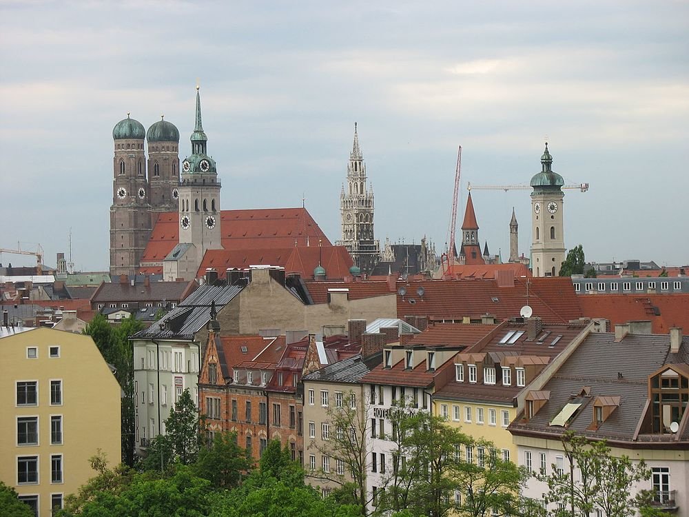 Munich city skyline with historic churches and rooftops Panoramic view of Munich city skyline featuring historic churches and traditional Bavarian architecture under a cloudy sky