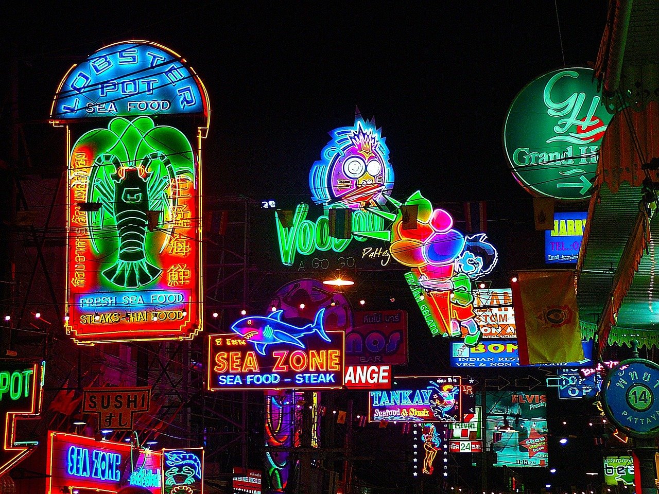 Neon seafood and nightlife signs at night Vibrant neon signs advertising seafood restaurants and nightlife in a busy urban street at night.