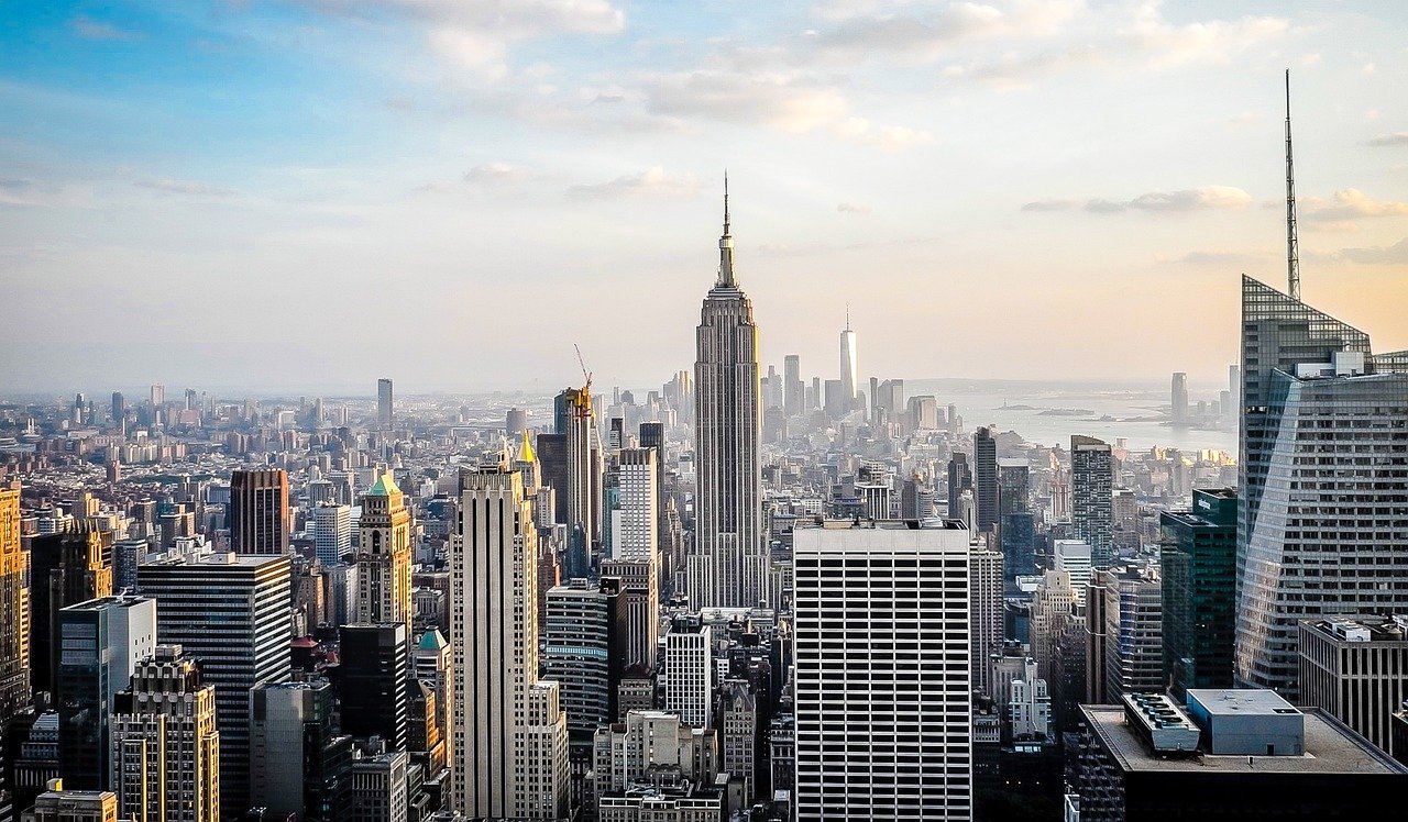 Panoramic view of New York City skyline featuring the Empire State Building and modern skyscrapers at sunset