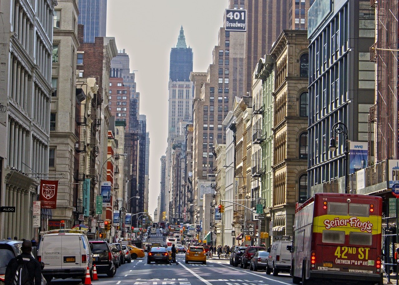 Busy New York City street with yellow taxis, tall buildings, and a red bus advertising Señor Frog's on 42nd Street