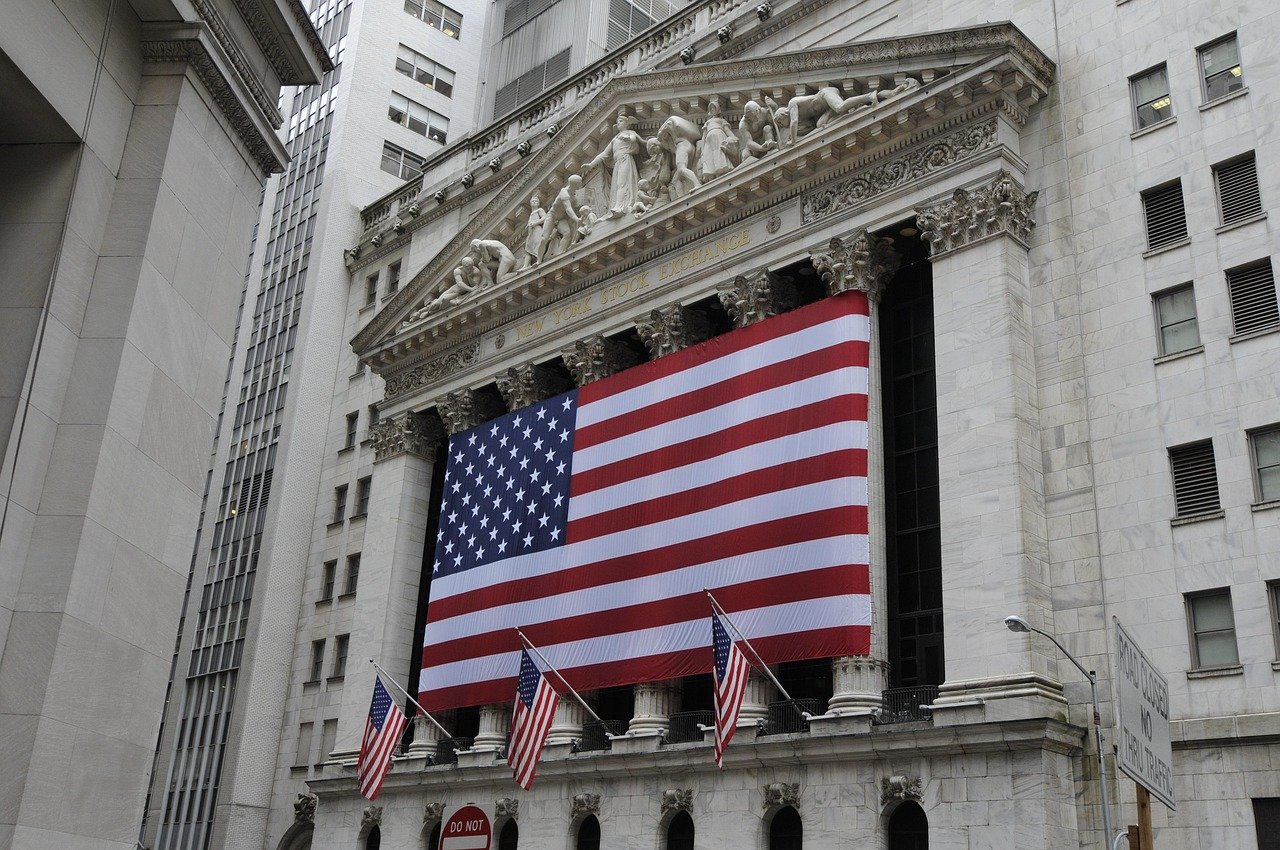 Front view of New York Stock Exchange building adorned with large American flag and smaller flags