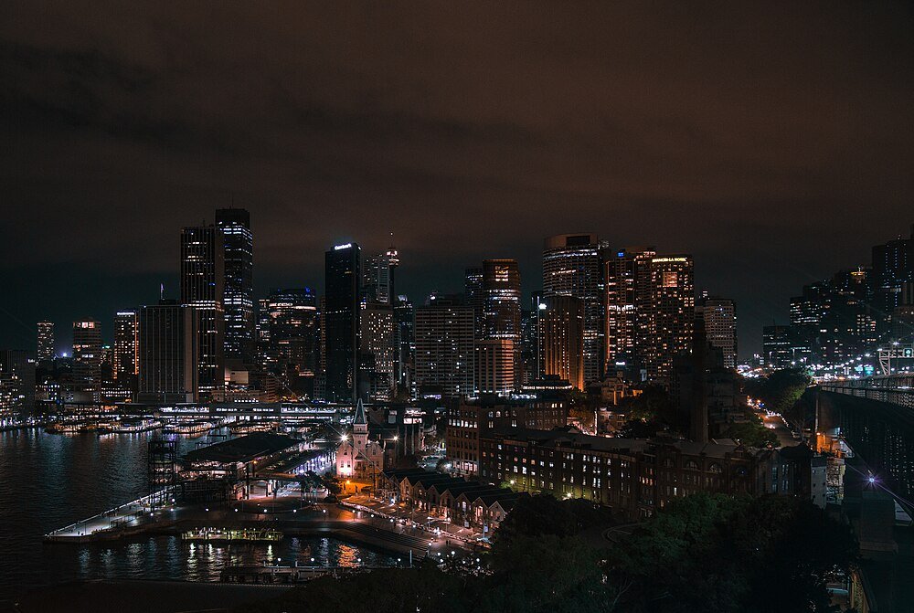 Nighttime city skyline with illuminated skyscrapers and waterfront reflecting lights in a modern urban area