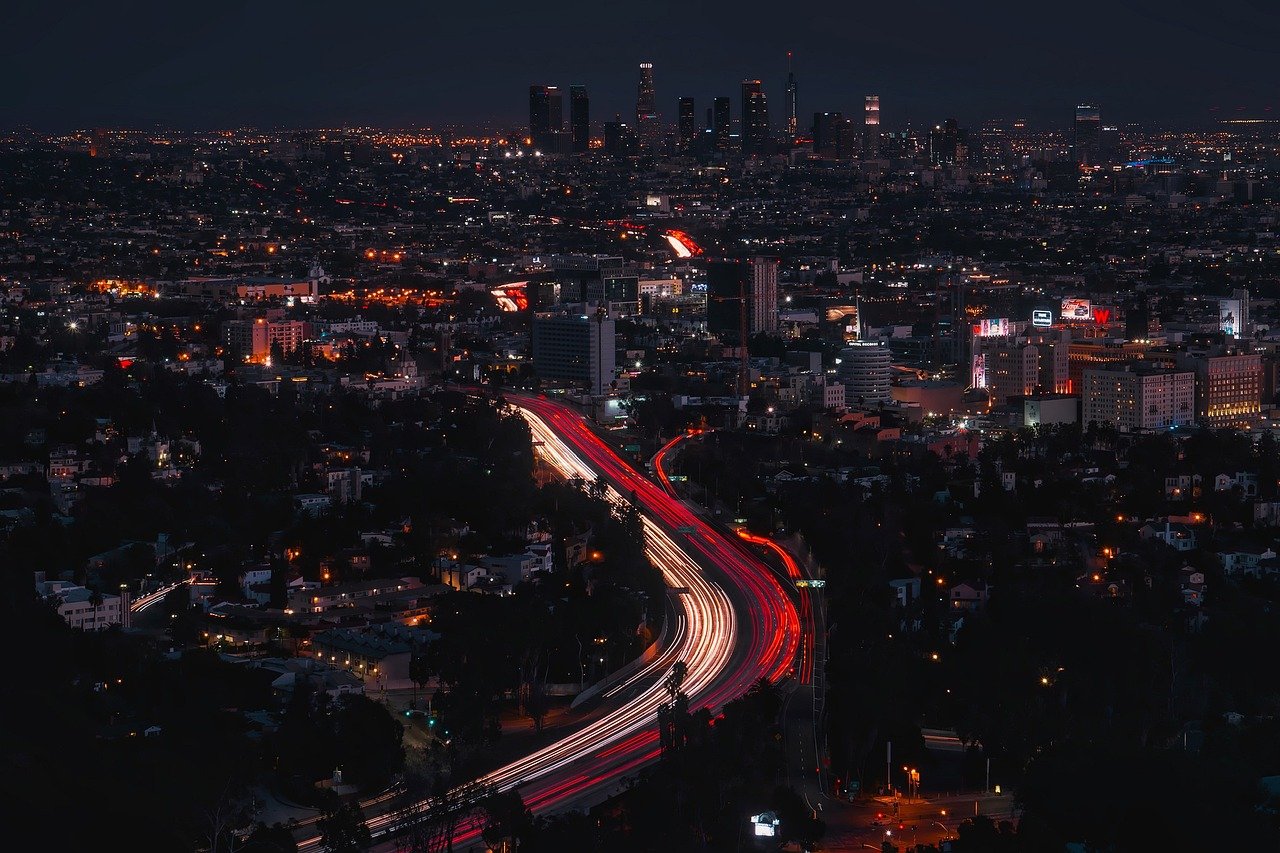 Nighttime cityscape with illuminated highway and light trails in a bustling urban area with skyscrapers