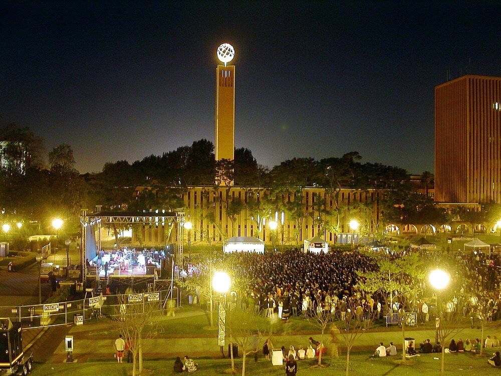 Night concert with crowd and clock tower Nighttime outdoor concert with large crowd and illuminated clock tower in background at university campus