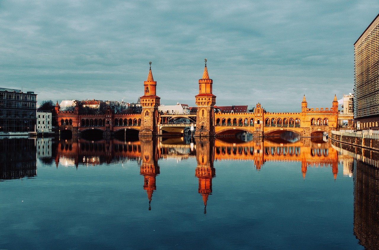 Oberbaum Bridge in Berlin reflected in calm river water under cloudy sky during daytime