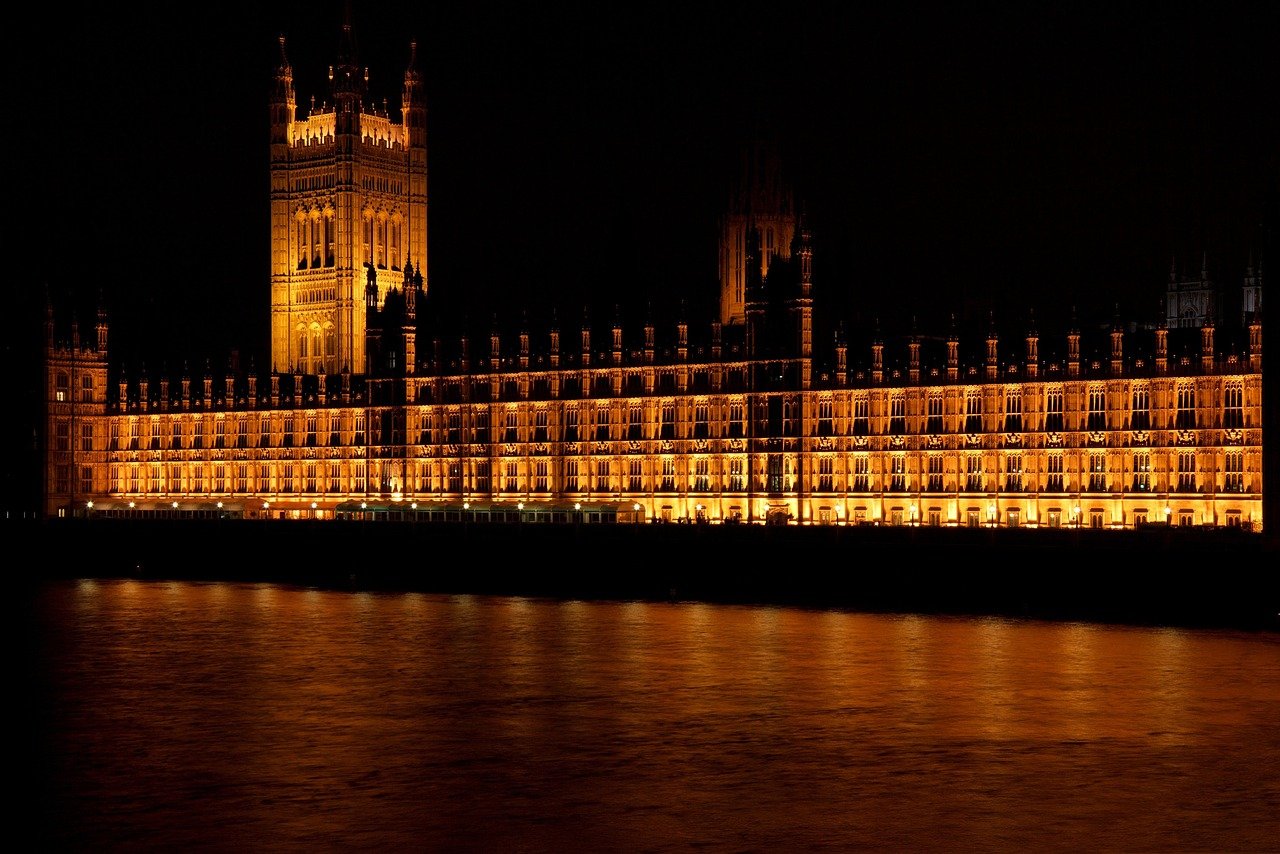 Illuminated Palace of Westminster at night reflecting on the River Thames in London, iconic UK landmark and government building
