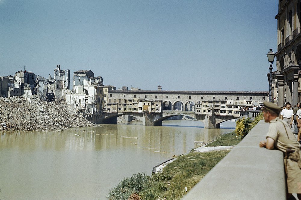 Ponte Vecchio Bridge and War-Damaged Buildings Florence Historic Ponte Vecchio bridge over the Arno River with damaged buildings and rubble on the riverbank in Florence, Italy
