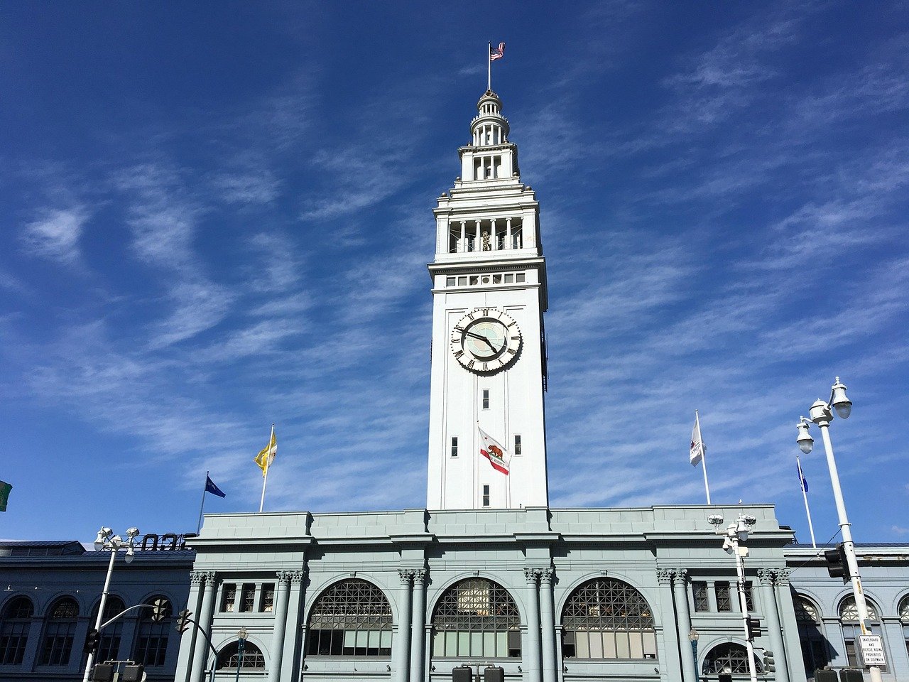 Historic San Francisco Ferry Building with clock tower under clear blue sky and American flag on top
