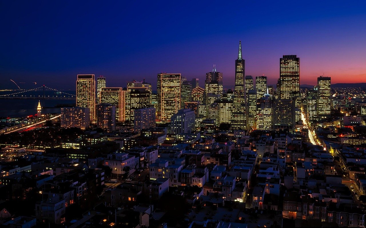 San Francisco city skyline at dusk with illuminated skyscrapers and the Bay Bridge in the background