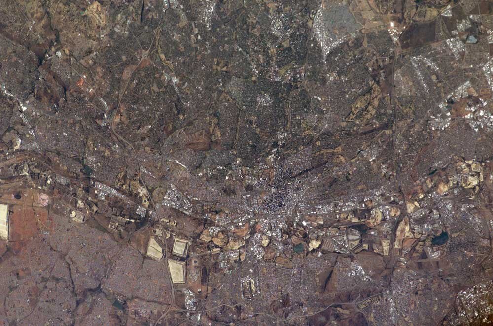Satellite view of dense urban cityscape Aerial satellite view of a densely populated urban area with roads, buildings, and open land patches