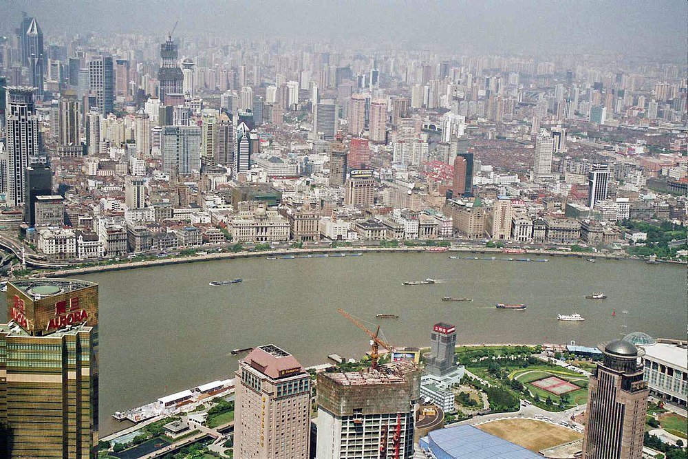 Aerial view of Shanghai city skyline with Huangpu River and numerous high-rise buildings and boats on the water