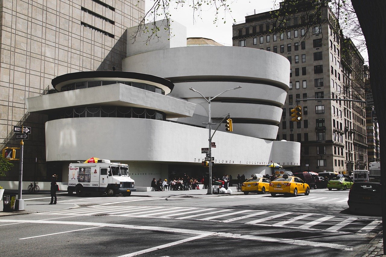 Exterior view of the Solomon R. Guggenheim Museum in New York City with yellow taxis and an ice cream truck nearby