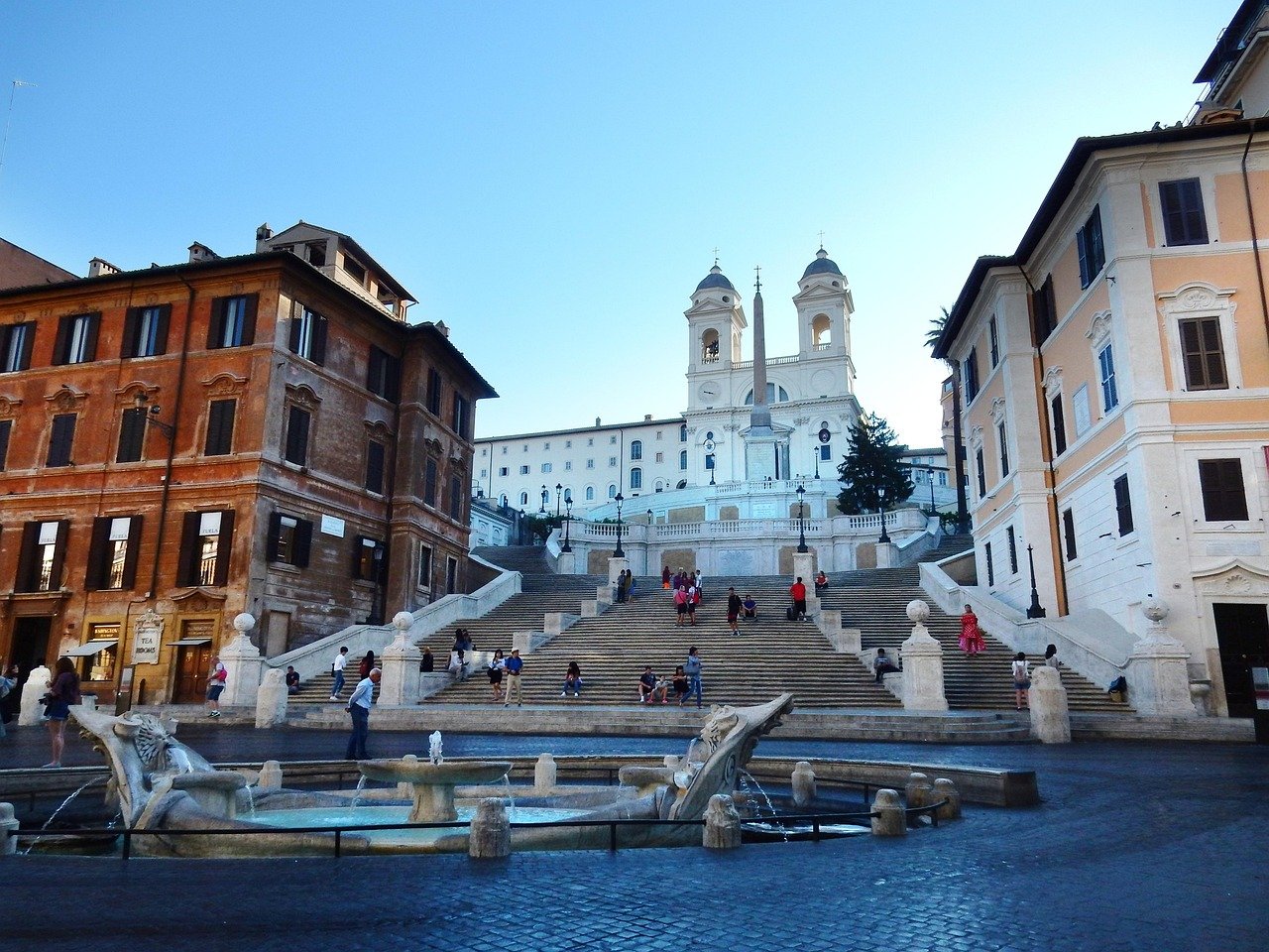 Spanish Steps in Rome with tourists, historic buildings, and Fontana della Barcaccia fountain in foreground