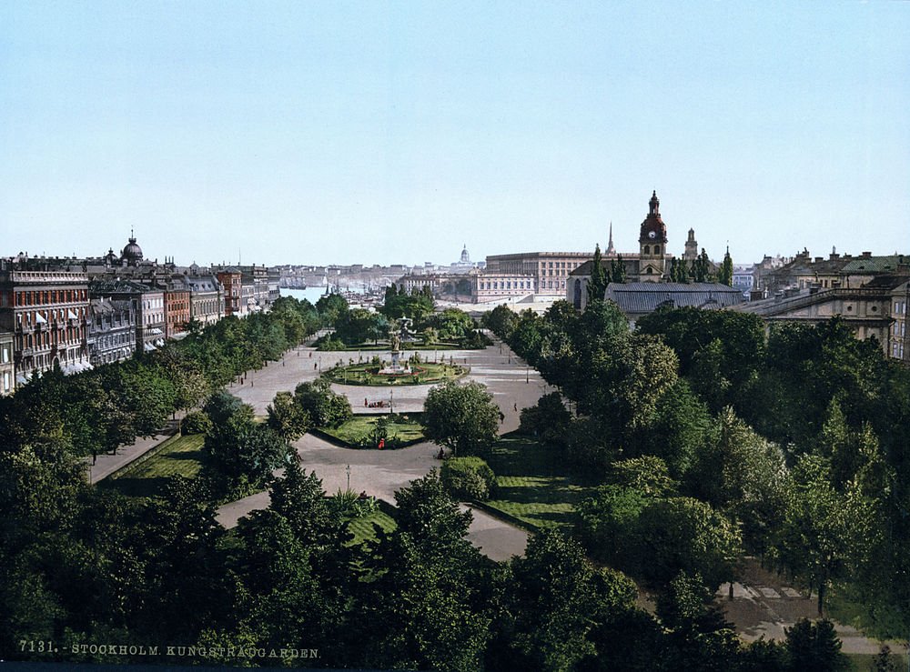 Scenic view of Kungsträdgården park in Stockholm with lush greenery, historic buildings, and clear blue sky