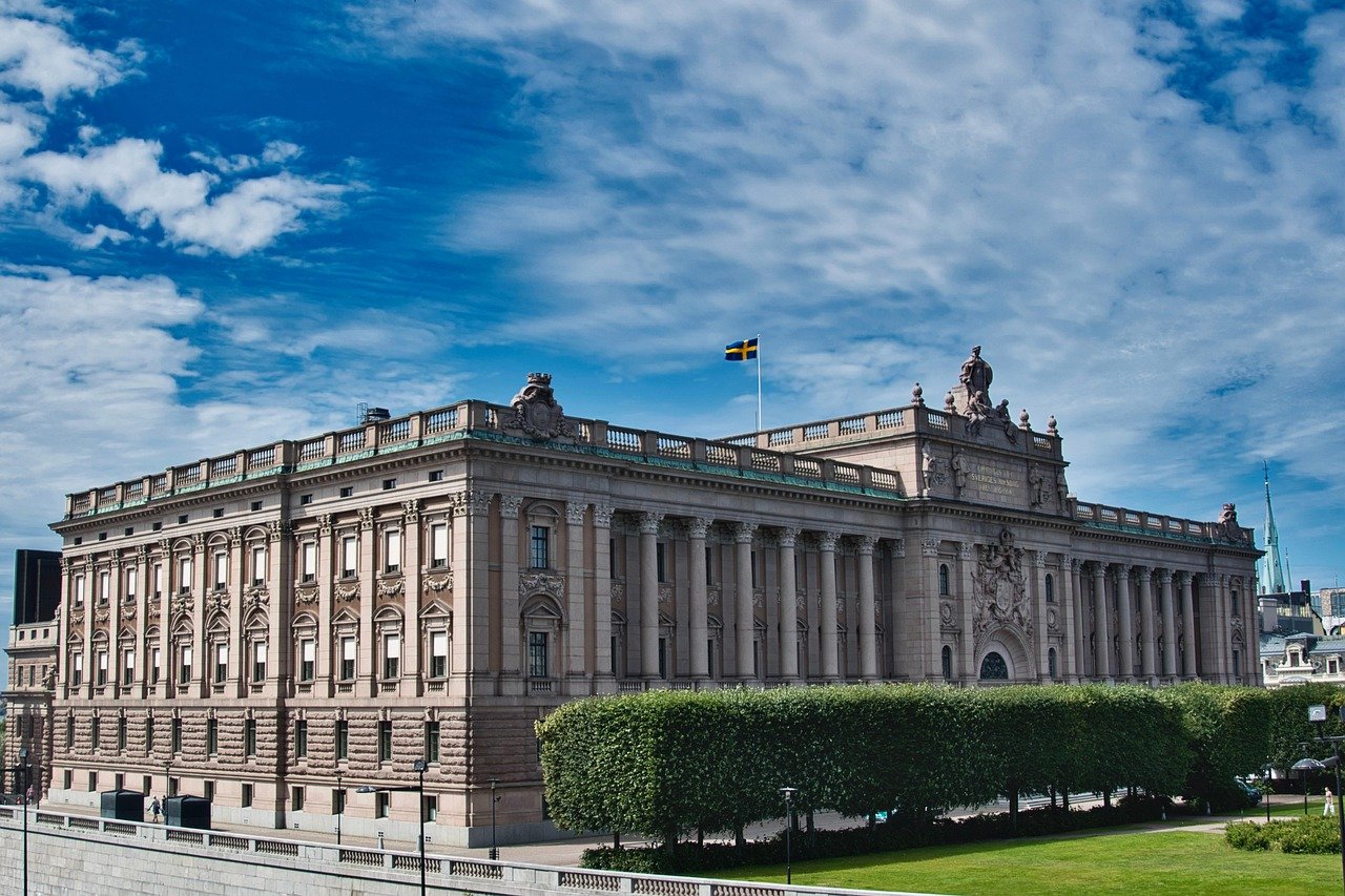 Historic Swedish Royal Palace with detailed architecture and Swedish flag under a blue sky with clouds
