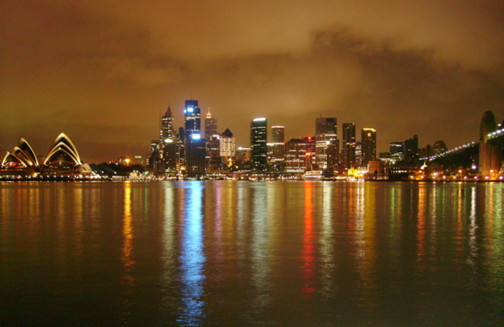 Sydney skyline at night with Opera House and Harbour Bridge Nighttime view of Sydney skyline with illuminated Opera House and Harbour Bridge reflecting on water