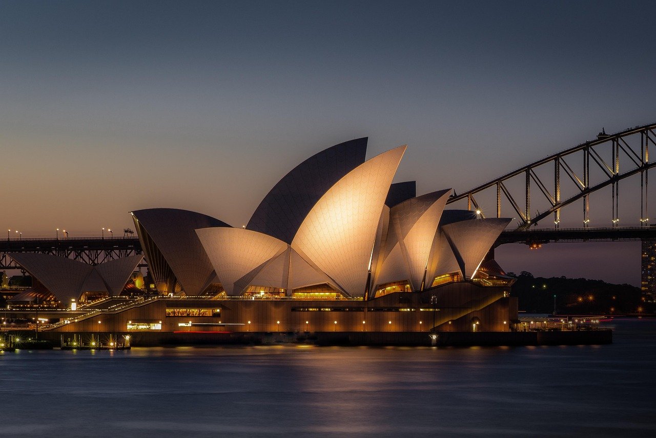 Sydney Opera House illuminated at dusk with Sydney Harbour Bridge in the background, iconic Australian landmark