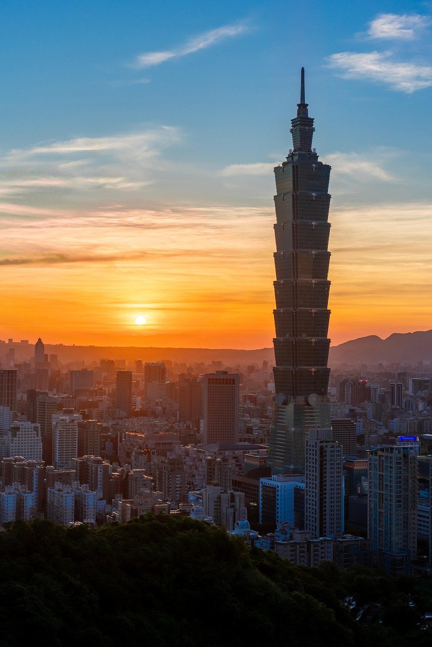Taipei 101 skyscraper towering over Taipei city skyline during a vibrant sunset with colorful sky and urban buildings