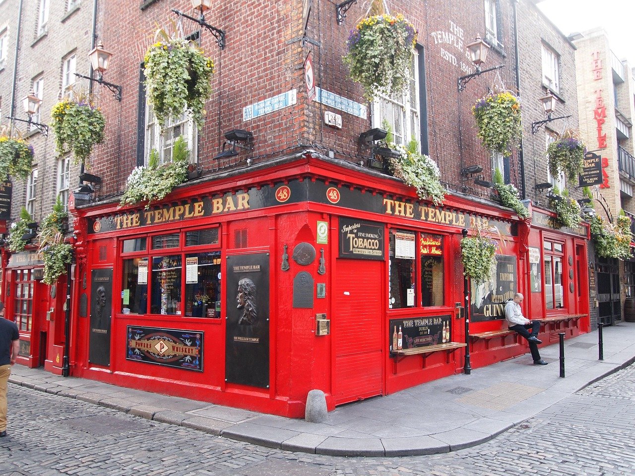 The Temple Bar Dublin iconic red pub with hanging flower baskets and cobblestone street corner