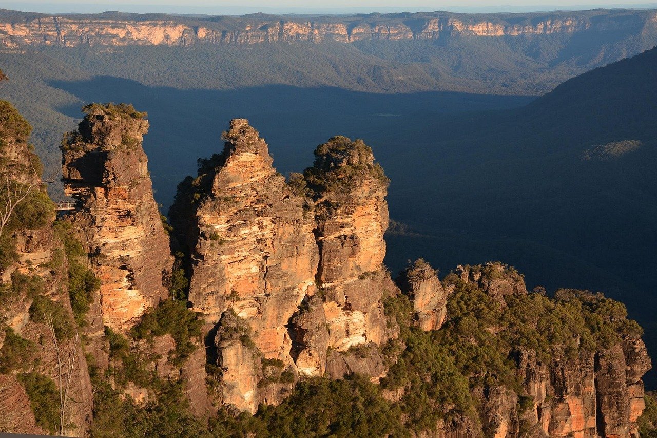 Scenic view of the Three Sisters rock formation in Blue Mountains National Park, Australia during sunset with lush greenery