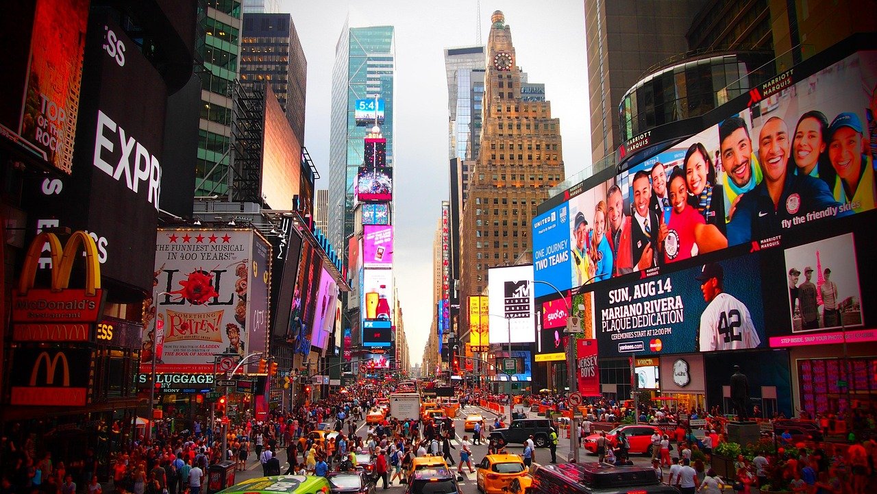 Busy Times Square in New York City with crowds, yellow taxis, and vibrant digital billboards advertising brands and events