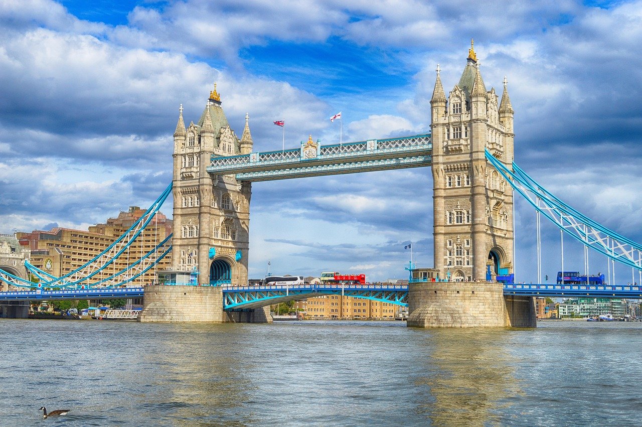Tower Bridge in London over the River Thames with blue sky and passing red double-decker bus