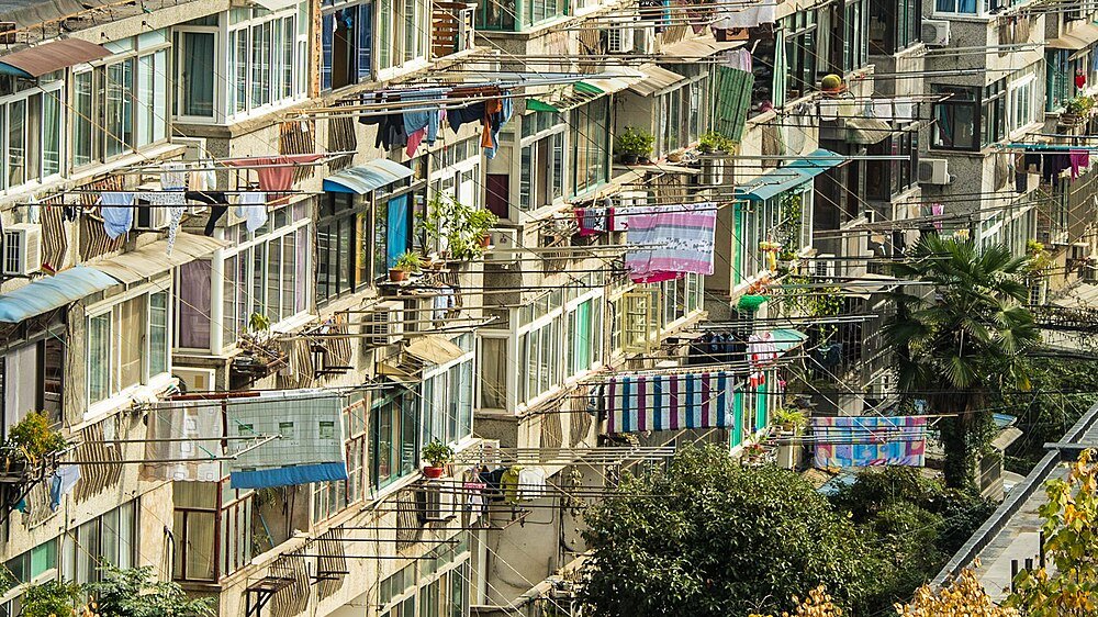 Apartment building exterior with multiple windows and colorful clothes hanging on drying racks in urban area