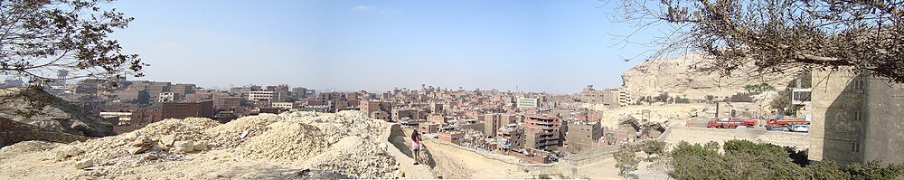Panoramic urban cityscape with rocky foreground Panoramic view of a densely populated urban area with residential buildings and rocky terrain under a clear sky