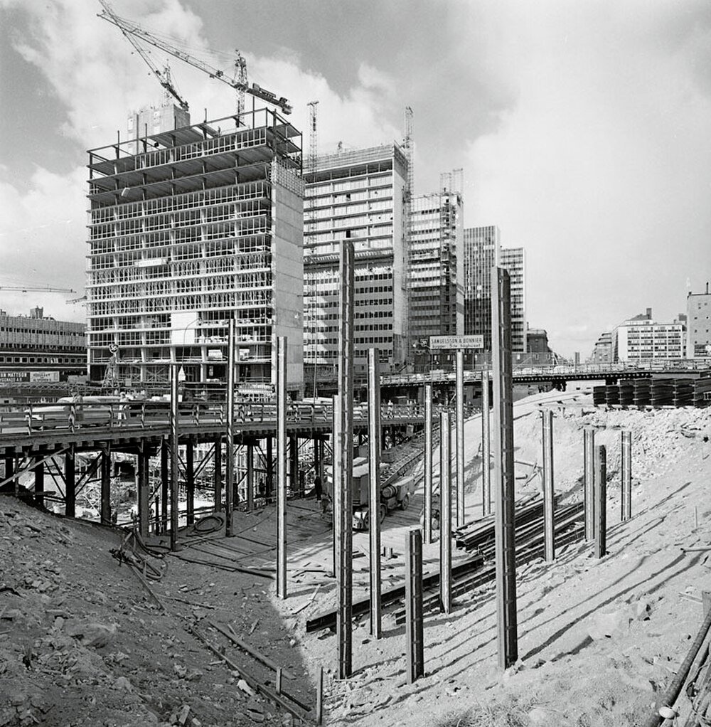 Black and white photo of a large urban construction site with cranes and partially built high-rise buildings
