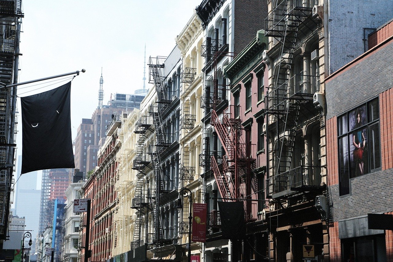 Urban street view with classic fire escapes on colorful buildings in a busy city neighborhood under daylight